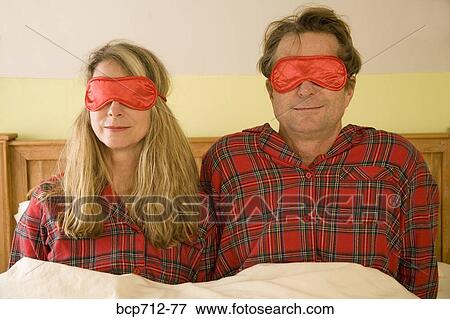 Couple sitting in bed wearing eye masks View Large Photo Image Stock Photo - Couple sitting in bed wearing eye masks. Fotosearch