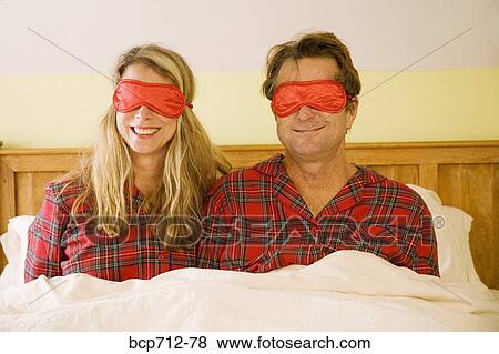 Couple sitting in bed wearing eye masks View Large Photo Image Stock Photo - Couple sitting in bed wearing eye masks. Fotosearch