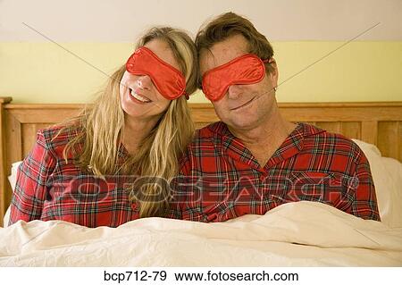 Couple sitting in bed wearing eye masks View Large Photo Image Stock Photo - Couple sitting in bed wearing eye masks. Fotosearch