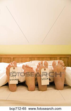 Couple’s bare feet with Do Not Disturb Til Noon signs View Large Photo Image Stock Photography - Couple’s bare feet with Do Not Disturb Til Noon signs. Fotosearch