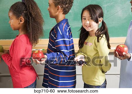 Girl holding spider in line to give apples to teacher View Large Photo Image Stock Image - Girl holding spider in line to give apples to teacher. Fotosearch