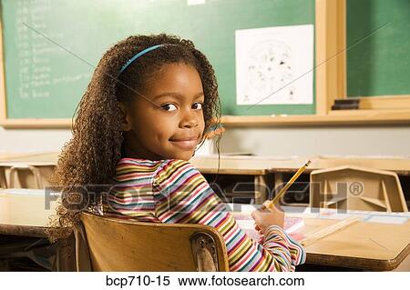 Girl looking over shoulder in classroom View Large Photo Image Stock Photography - Girl looking over shoulder in classroom. Fotosearch