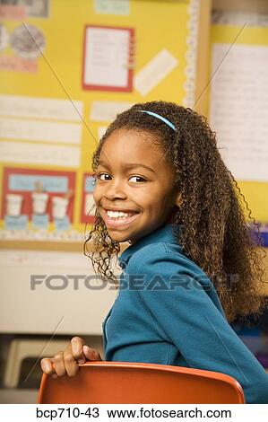 Girl smiling over shoulder in classroom View Large Photo Image Stock Image - Girl smiling over shoulder in classroom. Fotosearch