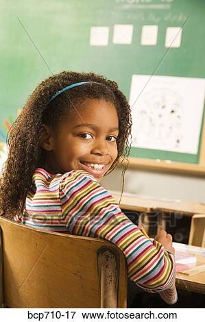 Girl smiling over shoulder in classroom View Large Photo Image Stock Photo - Girl smiling over shoulder in classroom. Fotosearch