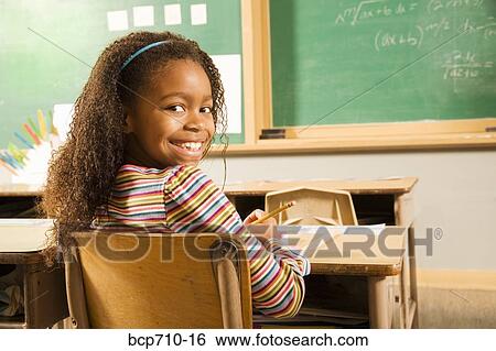 Girl smiling over shoulder in classroom View Large Photo Image Stock Photograph - Girl smiling over shoulder in classroom. Fotosearch