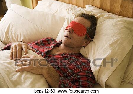 Stock Photo - Man sleeping with eye mask. Fotosearch