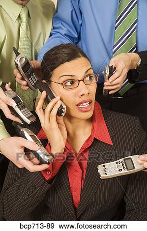 Stock Photo - Overwhelmed businesswoman surrounded by co-workers. Fotosearch