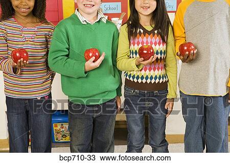 Portrait of children holding apples in classroom View Large Photo Image Stock Image - Portrait of children holding apples in classroom. Fotosearch