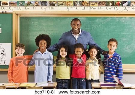 Stock Image - Portrait of male teacher and students in classroom. Fotosearch