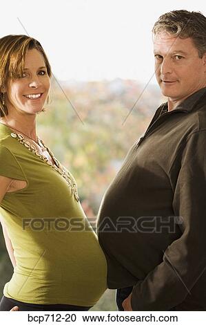 Stock Image - Portrait of pregnant couple touching bellies. Fotosearch