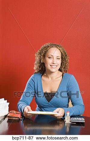 Stock Photo - Portrait of woman holding envelopes at desk. Fotosearch