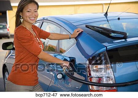 Stock Photo - Portrait of woman pumping gas. Fotosearch