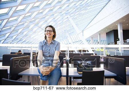 Portrait of woman sitting on desk View Large Photo Image Stock Photo - Portrait of woman sitting on desk. Fotosearch