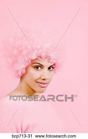 Stock Image - Portrait of woman wearing pink wig. Fotosearch