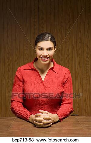 Stock Photo - Portrait of woman with hands clasped at table. Fotosearch