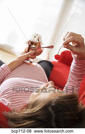Stock Photo - Pregnant woman eating ice cream sundae. Fotosearch
