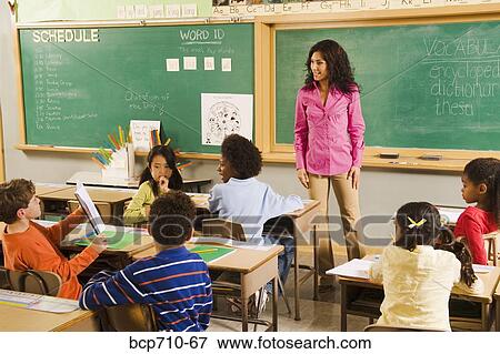Stock Photo - Student holding up work in classroom. Fotosearch