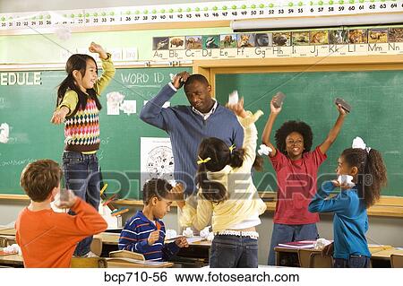 Students Having Paper Fight In Classroom Stock Photograph