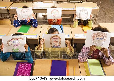 Students holding drawings over faces in classroom View Large Photo Image Stock Photo - Students holding drawings over faces in classroom. Fotosearch
