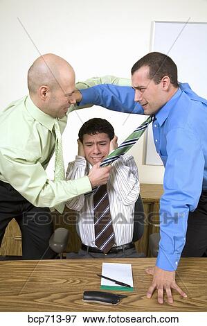 Two businessmen fighting above co-worker View Large Photo Image Stock Photo - Two businessmen fighting above co-worker. Fotosearch