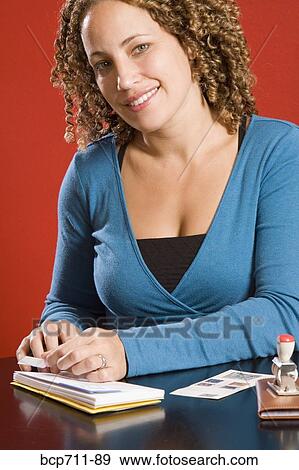 Stock Photo - Woman affixing stamp to envelope. Fotosearch