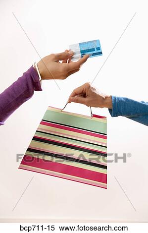 Woman handing credit card and clerk handing shopping bag View Large Photo Image Stock Photography - Woman handing credit card and clerk handing shopping bag. Fotosearch