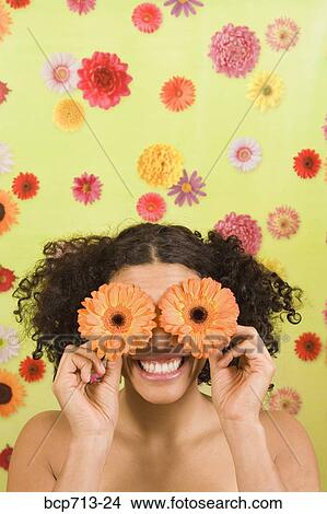Picture - Woman holding flowers over eyes. Fotosearch