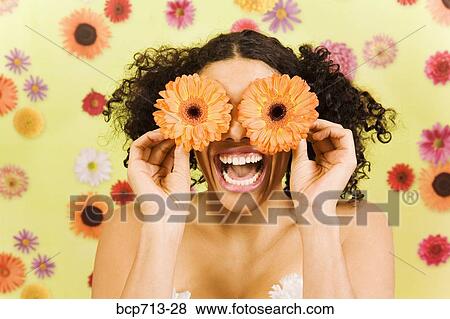 Woman laughing and holding flowers over eyes View Large Photo Image Stock Photo - Woman laughing and holding flowers over eyes. Fotosearch