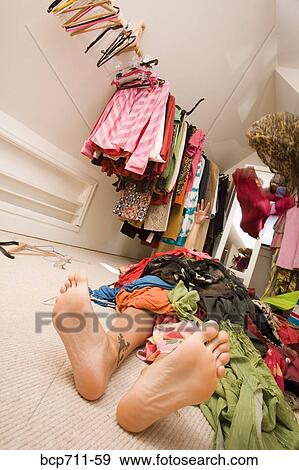 Woman laying under pile of clothes in closet View Large Photo Image Stock Photo - Woman laying under pile of clothes in closet. Fotosearch