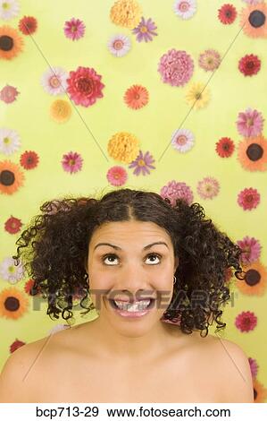 Stock Photo - Woman looking up in front of flower background. Fotosearch