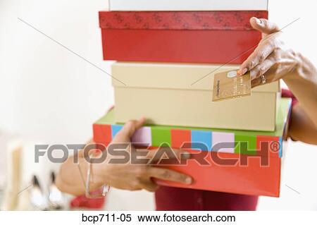 Stock Photography - Woman paying for stack of items at boutique. Fotosearch