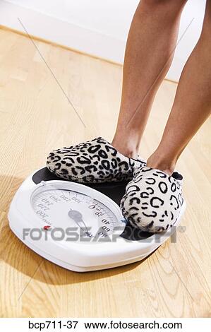 Woman standing on bathroom scale View Large Photo Image Stock Photo - Woman standing on bathroom scale. Fotosearch