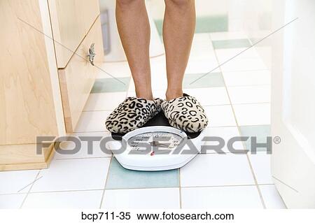 Woman standing on bathroom scale View Large Photo Image Stock Photography - Woman standing on bathroom scale. Fotosearch