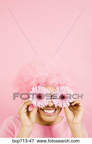 Woman wearing pink wig and holding flowers over eyes View Large Photo Image Stock Photo - Woman wearing pink wig and holding flowers over eyes. Fotosearch