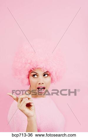 Stock Photograph - Woman wearing pink wig and pointing. Fotosearch
