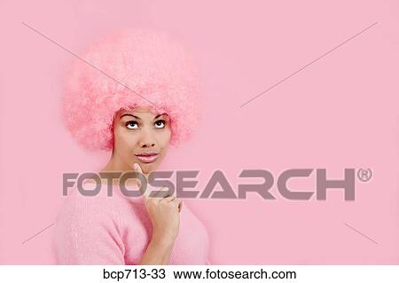 Stock Image - Woman wearing pink wig and thinking. Fotosearch