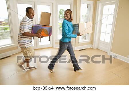 Picture - African couple carrying moving boxes. Fotosearch