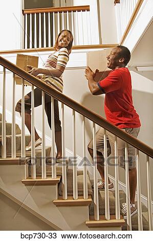 Stock Image - African couple carrying moving boxes. Fotosearch