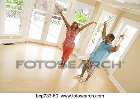Stock Image - African couple cheering in new house. Fotosearch