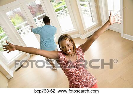 Stock Image - African couple cheering in new house. Fotosearch