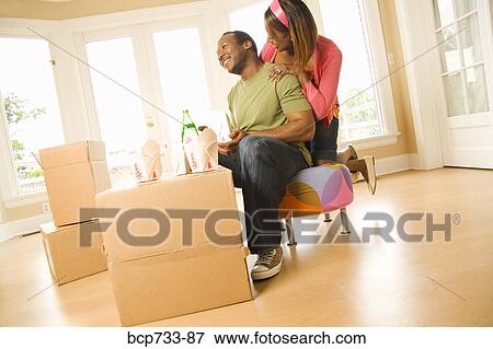 Stock Photo - African couple eating take out in new house. Fotosearch