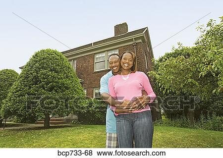 Stock Photo - African couple hugging in front of house. Fotosearch
