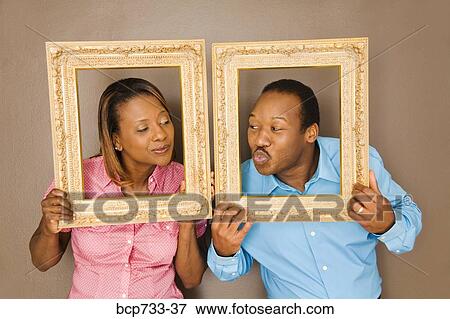 Stock Photo - African couple looking through picture frames. Fotosearch