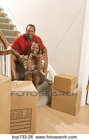 Stock Photograph - African couple next to moving boxes. Fotosearch