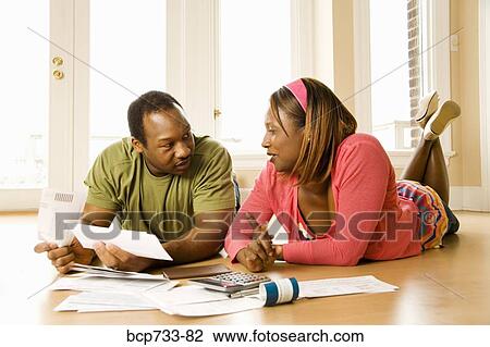 Stock Image - African couple paying bills in new house. Fotosearch