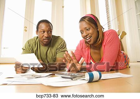 Stock Image - African couple paying bills in new house. Fotosearch