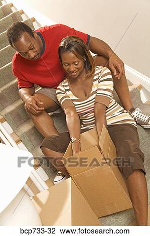 Stock Image - African couple unpacking moving boxes. Fotosearch