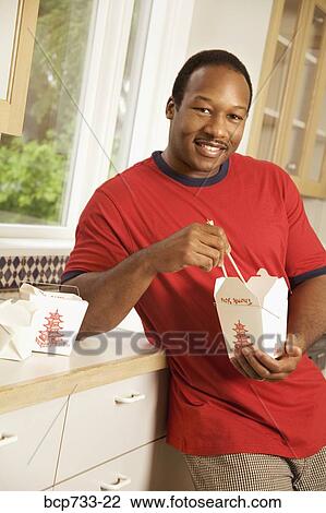 Stock Image - African man eating take out food. Fotosearch
