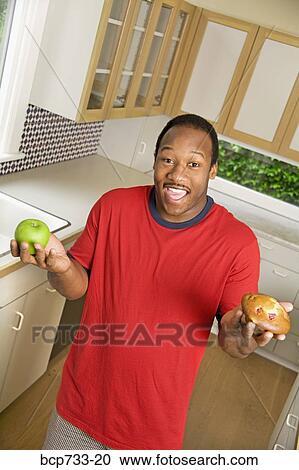 African man holding apple and muffin View Large Photo Image Stock Image - African man holding apple and muffin. Fotosearch
