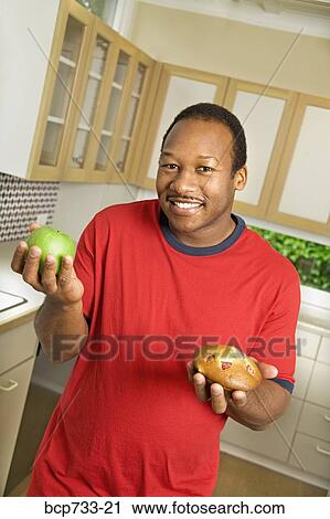 African man holding apple and muffin View Large Photo Image Stock Image - African man holding apple and muffin. Fotosearch